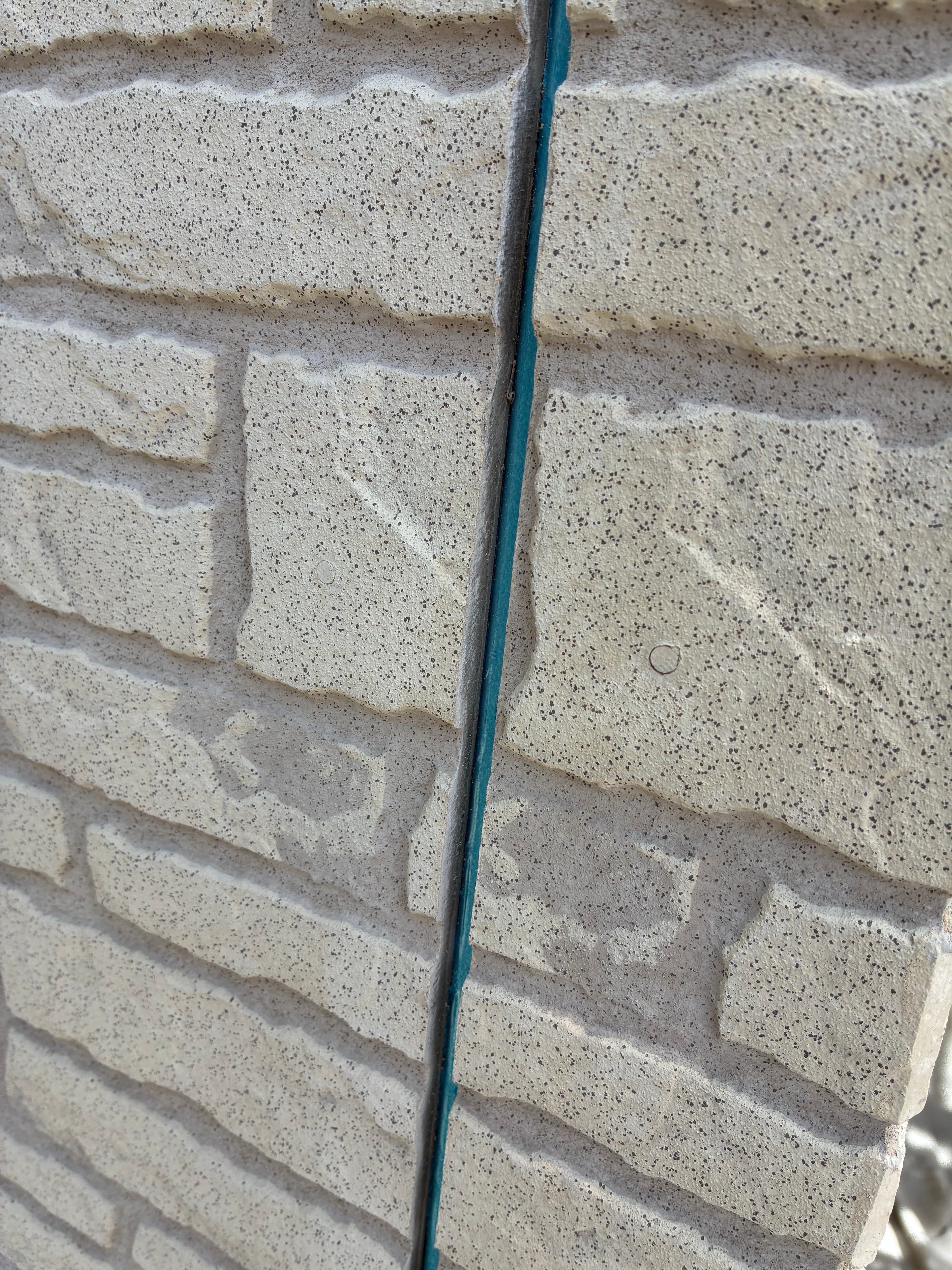 古いコーキング材を完全に除去している施工写真。マスキングテープで養生し、丁寧に下地処理を行っている様子